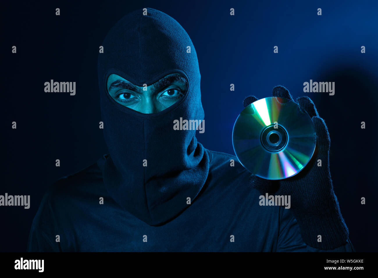 Hacker holding a pirated compact disc Stock Photo