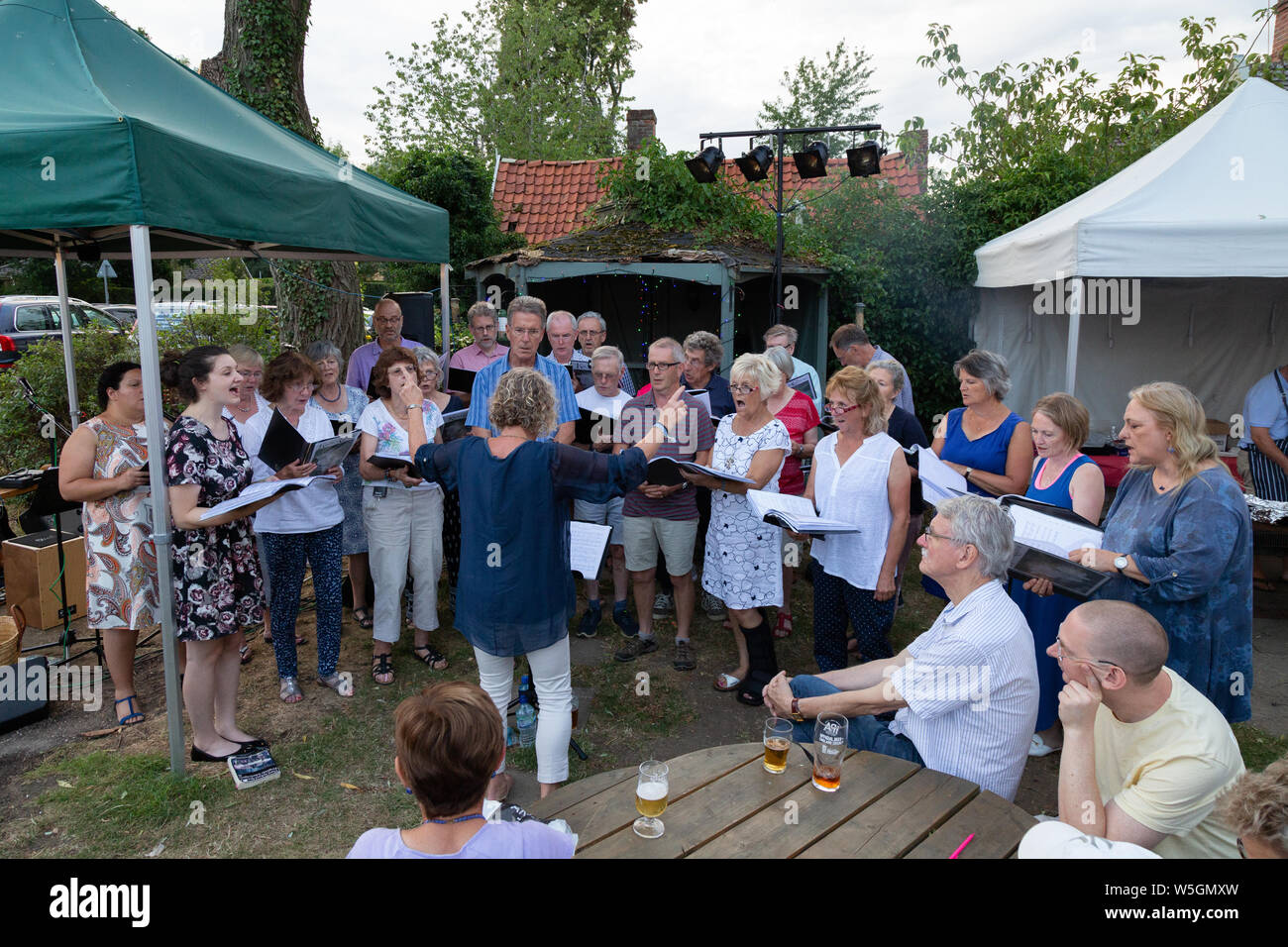 Local Choir singing; A group of people in a choir singing outside at a pub sing out, Burrough Green village, Cambridgeshire UK Stock Photo