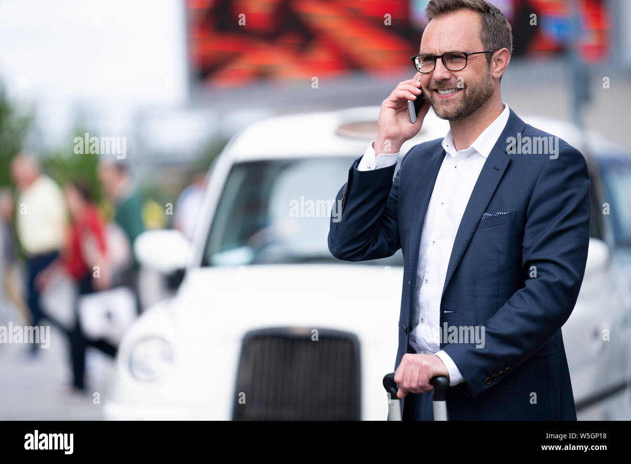 Mature Businessman Taking Phone Call On Mobile Standing By Taxi Rank Outside Railway Station Stock Photo