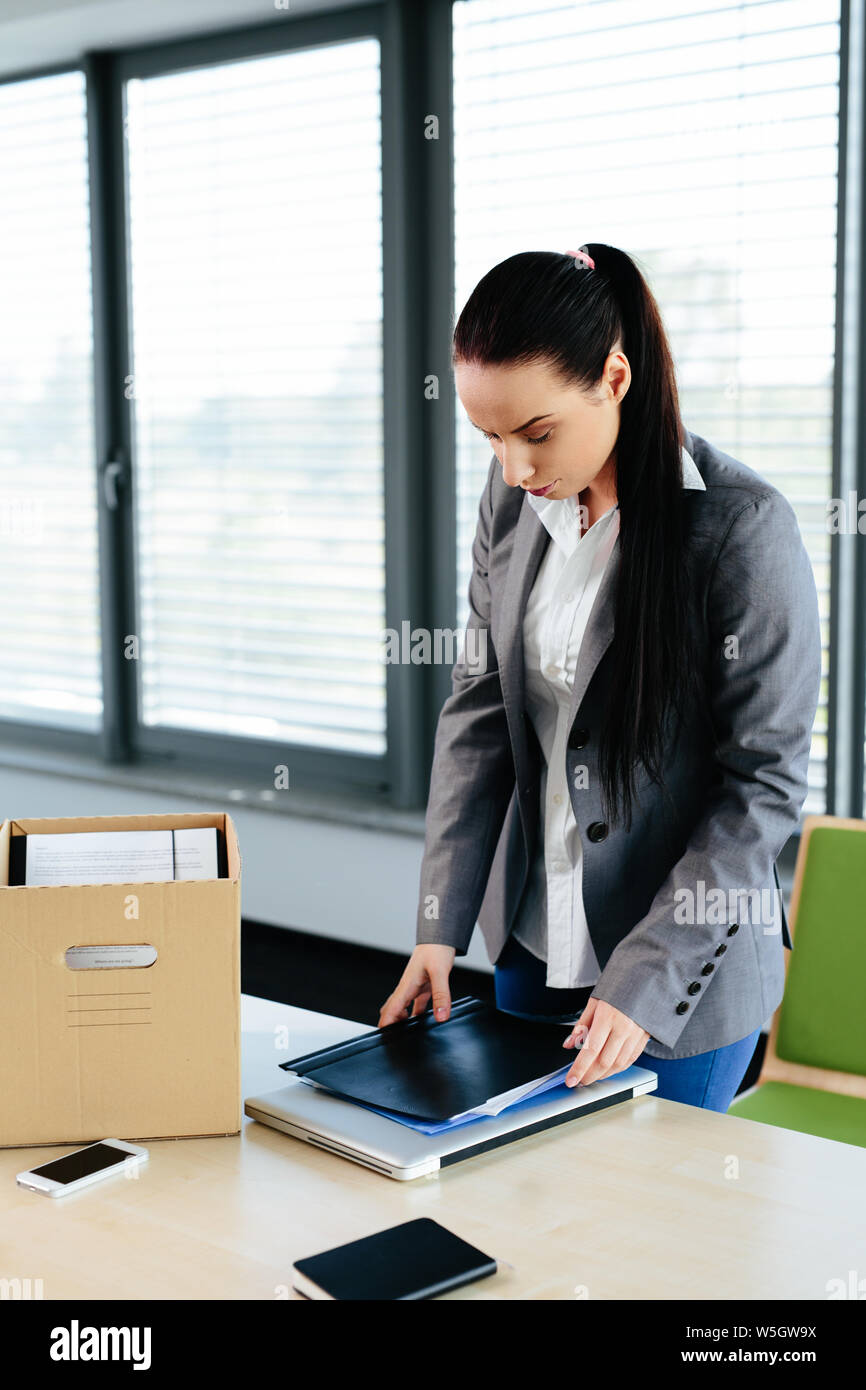 Photo of a female office worker packing her office things after being dismissed Stock Photo