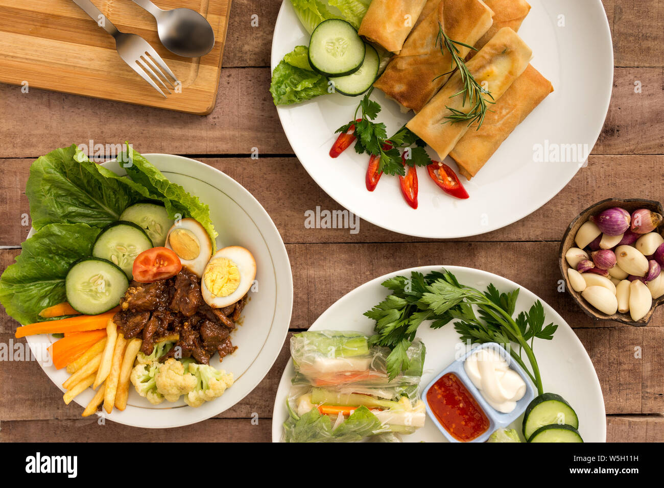 Asian style spring rolls  with mixed vegetables and satay beef on table - layflat food concept image Stock Photo