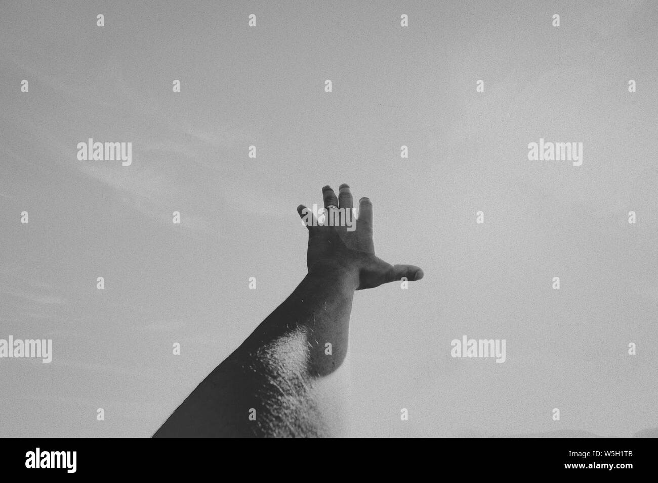 Black and white monochrome shot of a person's left hand on a wide surface Stock Photo