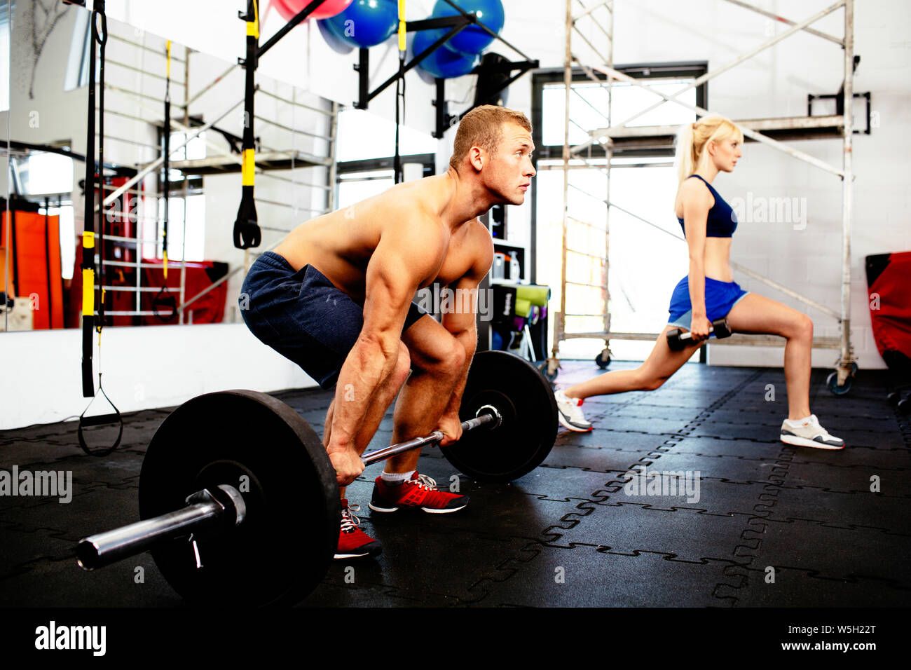 Young couple training with weights at gym Stock Photo