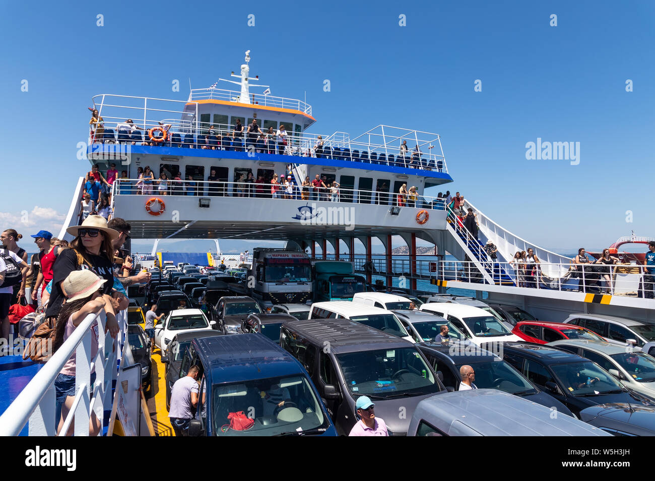 Thassos, Greece - July 20, 2019: Big ferry boat deck with passengers and cars, runs from Keramoti city to Thassos island. Stock Photo