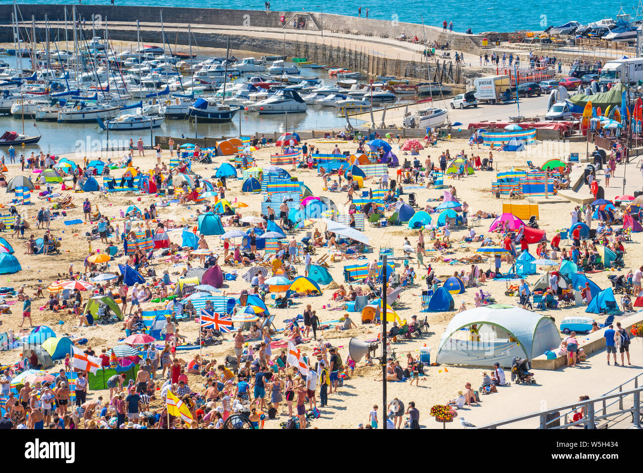 Lyme Regis, Dorset, UK. 29th July 2019. UK Weather: Another scorching hot start to the week at the picturesque seaside resort of Lyme Regis. Crowds of holidaymakers  and families pack out the beach to make the best of the baking hot sunshine over RNLI and Regatta week.  Credit: Celia McMahon/Alamy Live News. Stock Photo