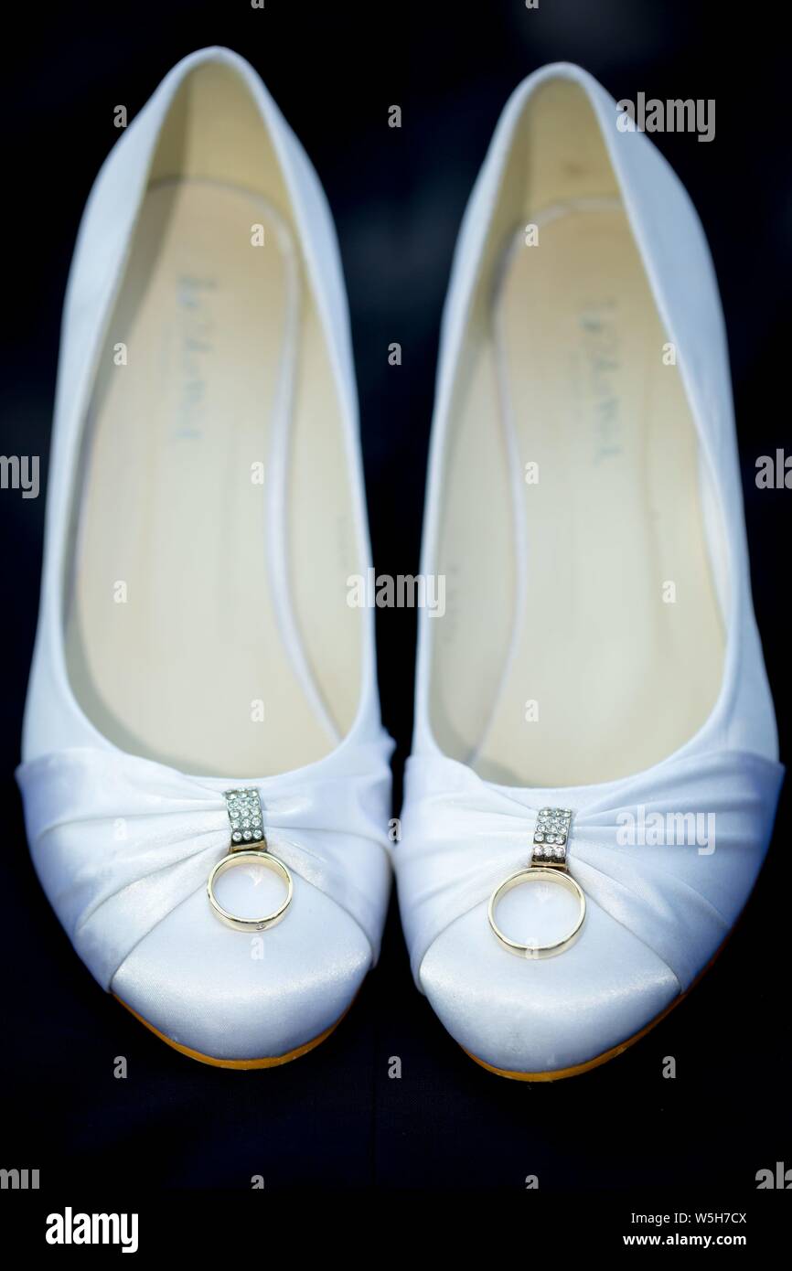 Symbolic photo on the subject of wedding and marriages. White wedding shoes with the wedding rings. | usage worldwide Stock Photo