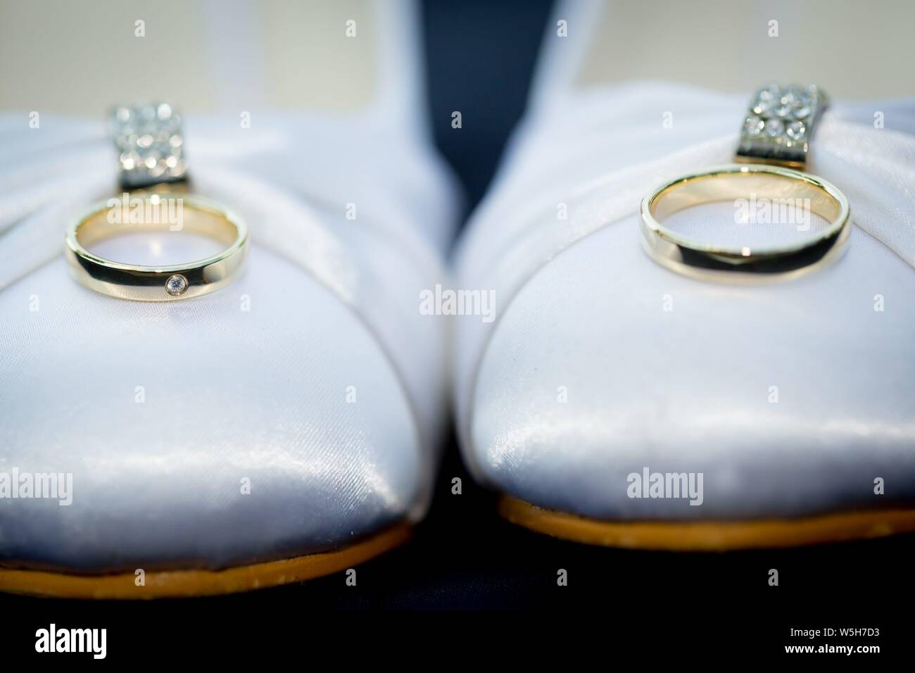 Symbolic photo on the subject of wedding and marriages. White wedding shoes with the wedding rings. | usage worldwide Stock Photo