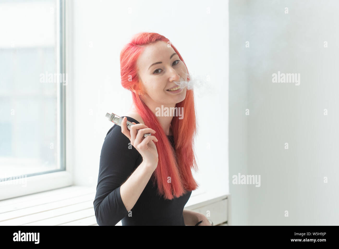 Vape, addiction and people concept - woman with red hair is smoking vape  Stock Photo - Alamy