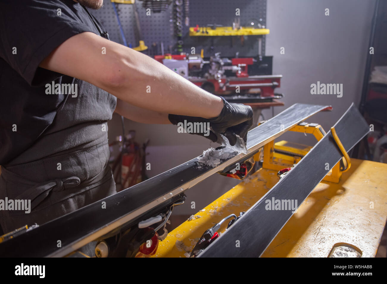 Work and repair concept - a man's hands repairing the ski by rubbing a paraffin Stock Photo