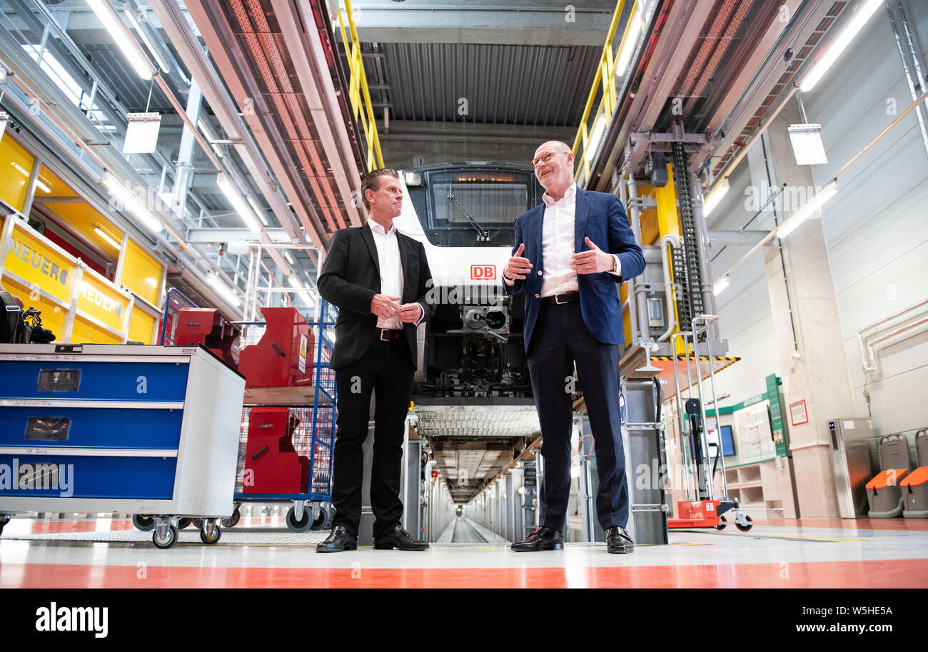 Hamburg, Germany. 29th July, 2019. Michael Westhagemann (r, non-party), Hamburg Senator for Economic Affairs, and Kay Uwe Arnecke, Managing Director of S-Bahn Hamburg, speak during a visit by the Senator to the new Stellingen S-Bahn maintenance plant. In the background is a class 490-618 train. Credit: Daniel Reinhardt/dpa/Alamy Live News Stock Photo