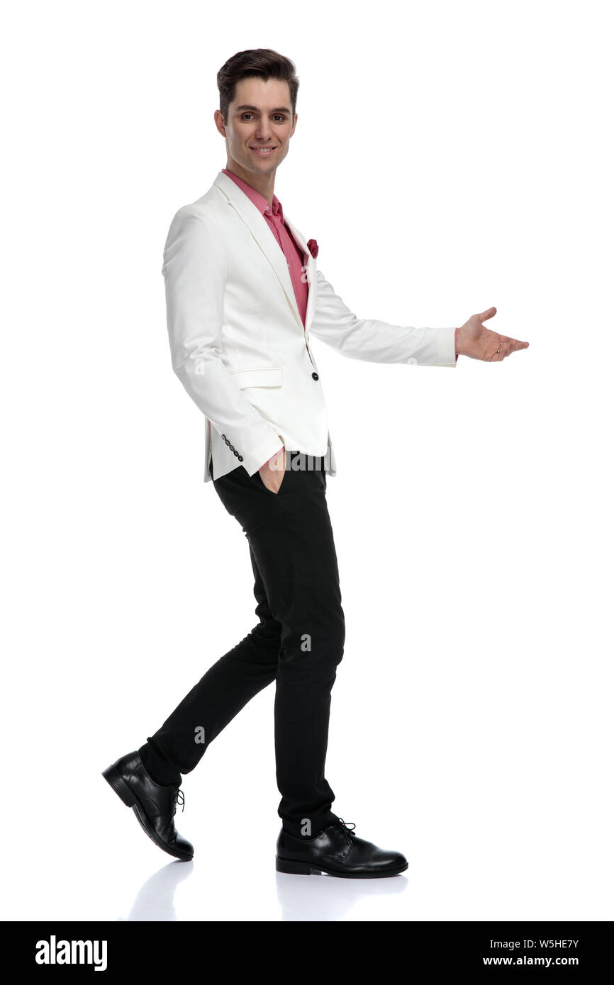 side view of a welcoming young businessman walking on white background ...