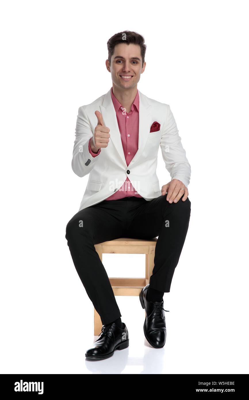 seated young elegant man makes the ok sign on white background Stock ...