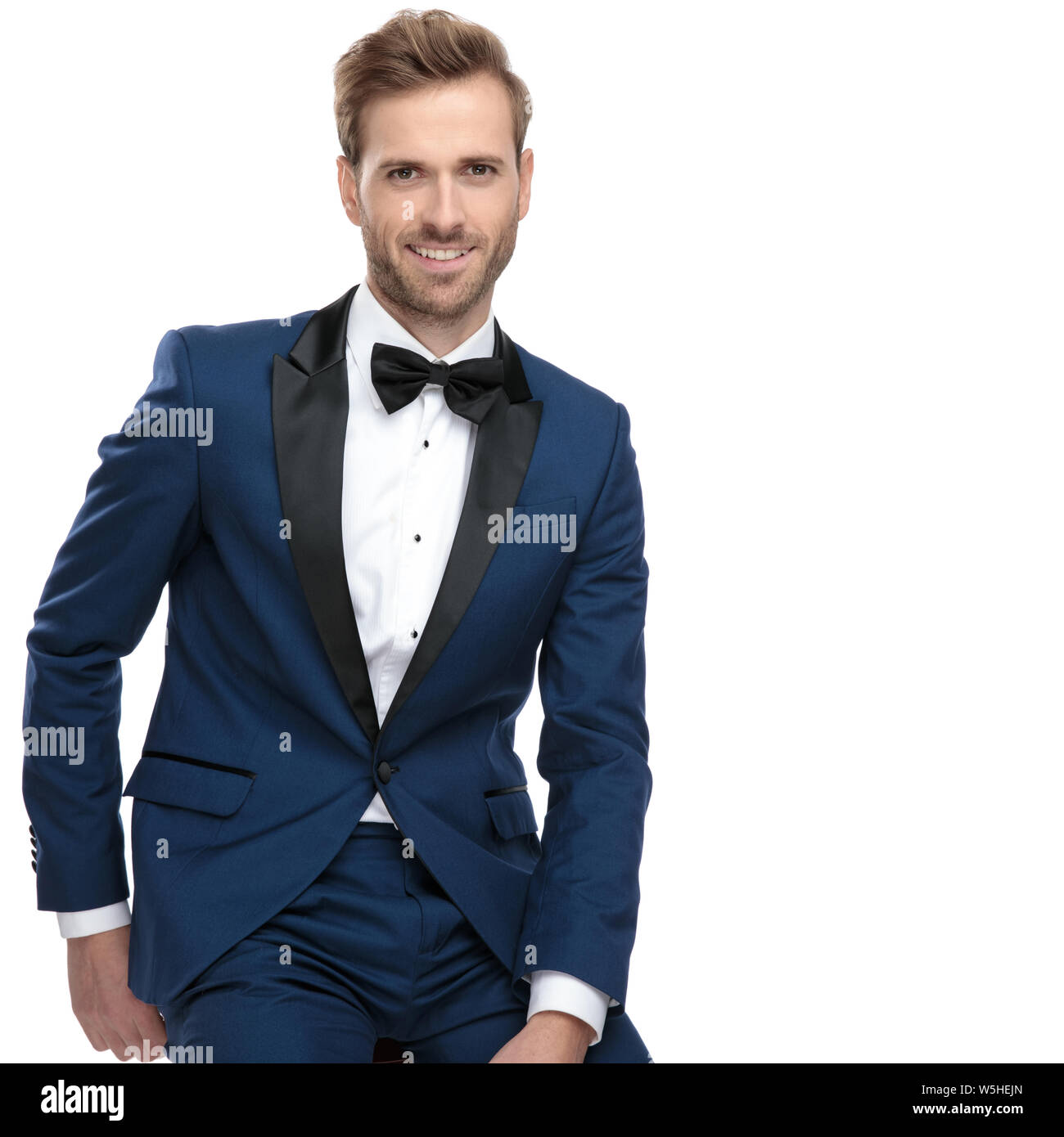 elegant guy in blue costume sitting with hand at back on white ...