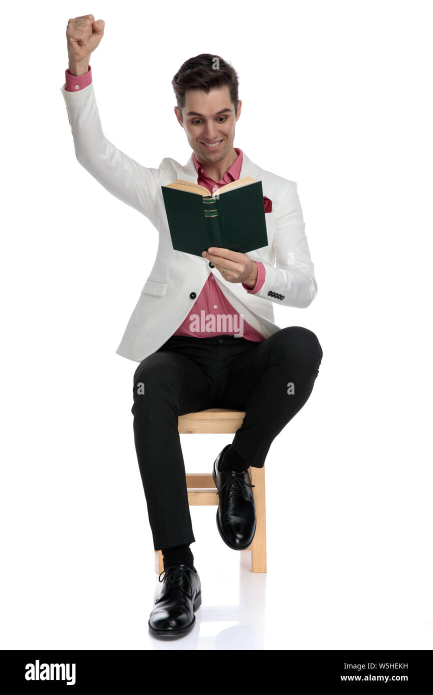 elegant man celebrating knowledge while sitting and reading a good book ...