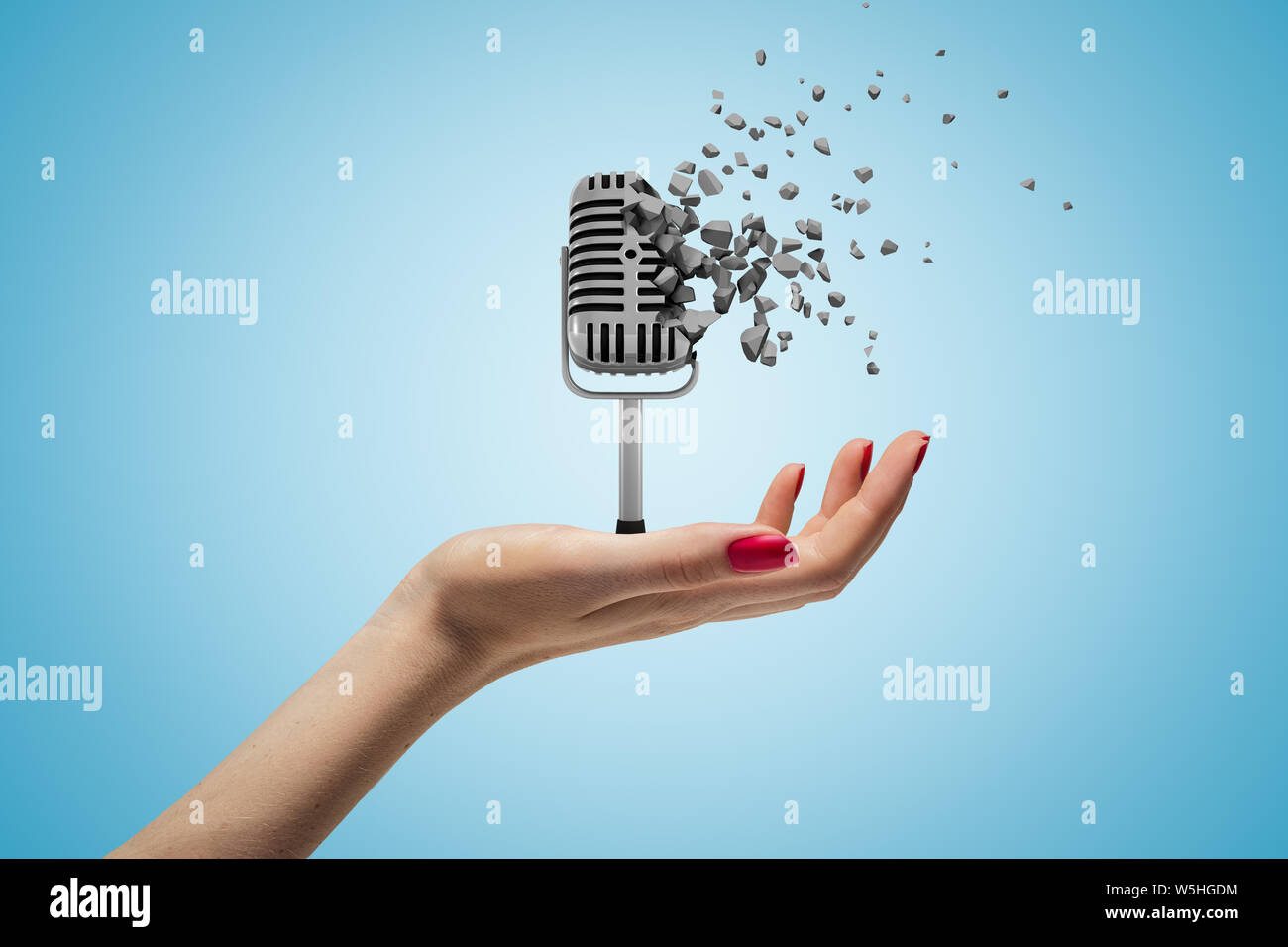 Female hand holding vintage microphone shattering into pieces on blue ...
