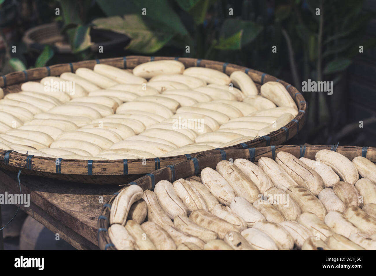 Peeled bananas drying in bamboo baskets exposed to the sun in Laos Stock Photo