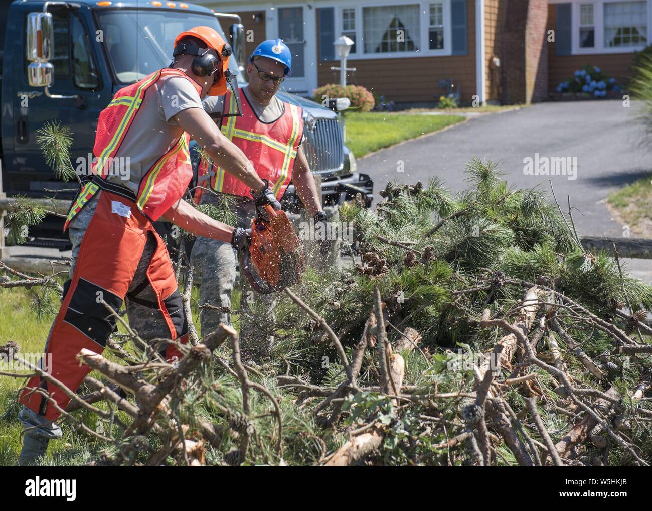 Airmen from the Massachusetts Air National Guard's 102nd Civil Engineer Squadron mobilized to support recovery efforts in the wake of two tornadoes that touched down on Cape Cod on July 23, 2019, July 25, 2019. The Airmen cleared fallen trees and debris from roadways in the towns of Dennis and Harwich Massachusetts. Image courtesy Tech. Sgt. Thomas Swanson/102nd Intelligence Wing. () Stock Photo
