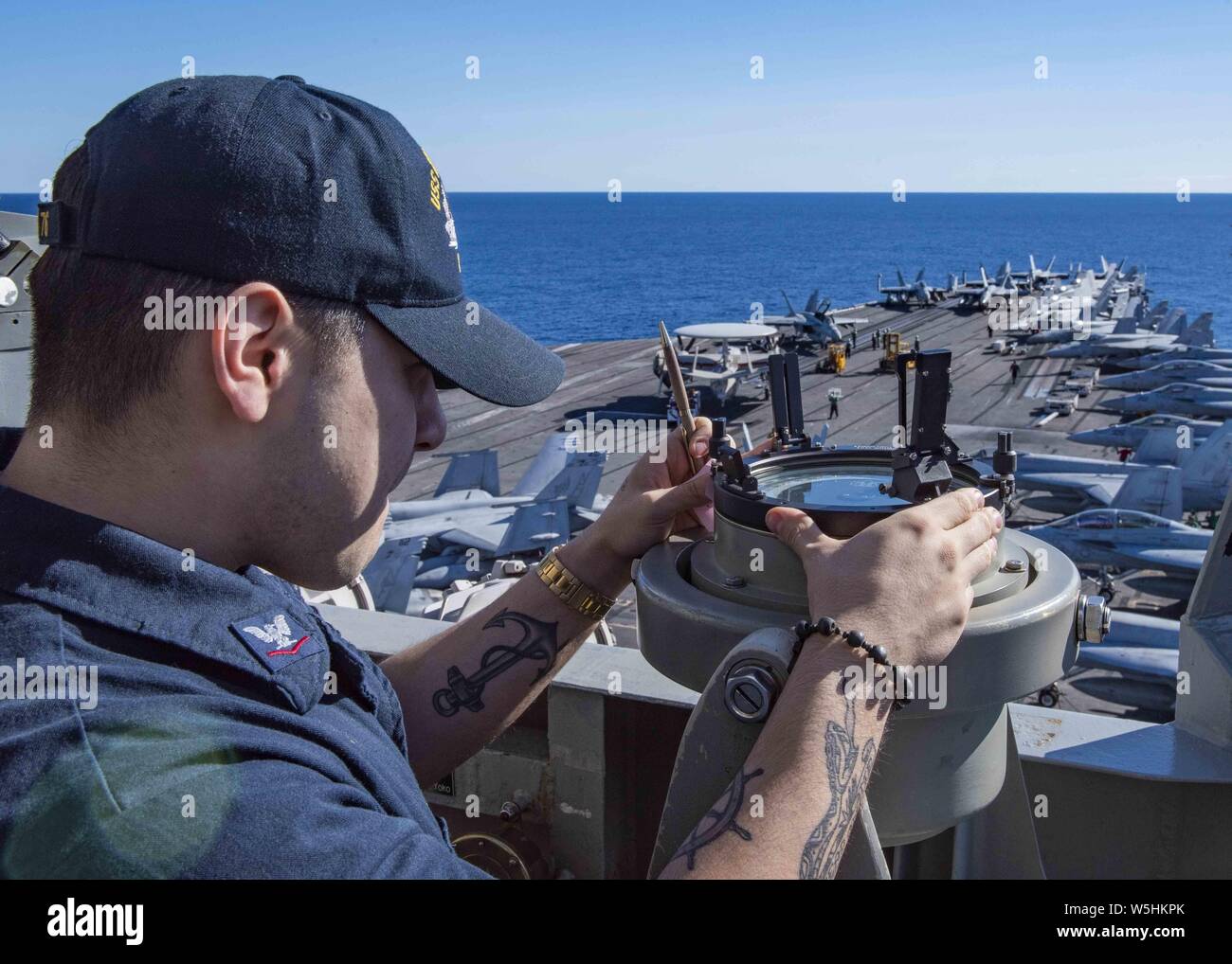 190725-N-DL524-0055 CORAL SEA (July 25, 2019) Quartermaster 3rd Class Payton Sanchez, from Corpus Christi, Texas, obtains the sun's azimuth at the forward lookout station aboard the Navy's forward-deployed aircraft carrier USS Ronald Reagan (CVN 76), July 25, 2019. Ronald Reagan, the flagship of Carrier Strike Group 5, provides a combat-ready force that protects and defends the collective maritime interests of its allies and partners in the Indo-Pacific region. (U.S. Navy photo by Mass Communication Specialist 3rd Class Erica Bechard) Image courtesy Petty Officer 3rd Class Erica Bechard/USS RO Stock Photo