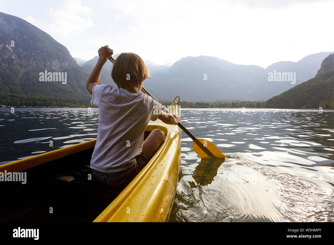 child in the front of a canoe paddling on the calm Bohinj lake, Slovenia, Europe Stock Photo