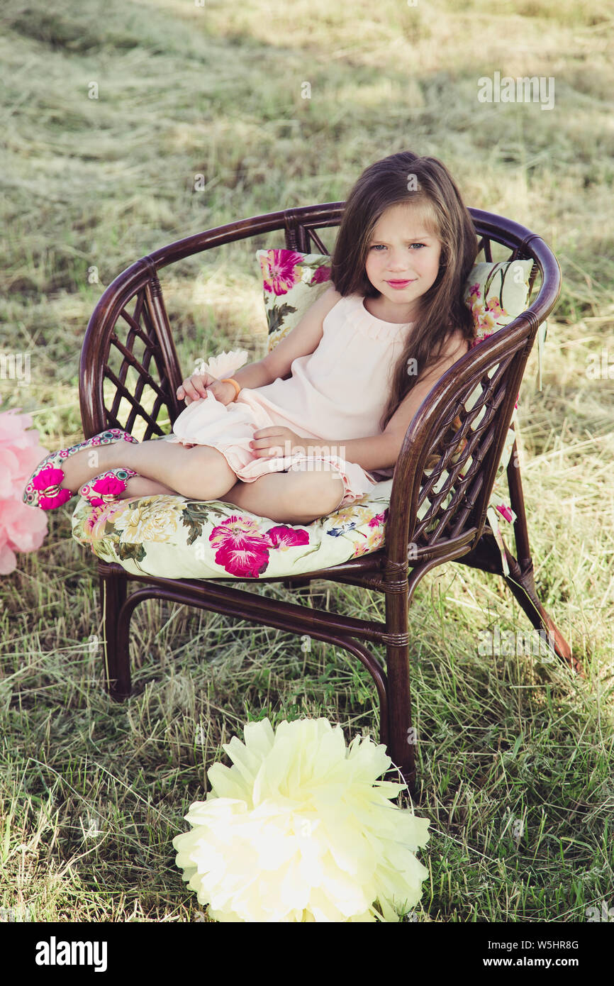 beautiful little girl with flowing hair sitting in a wicker chair ...