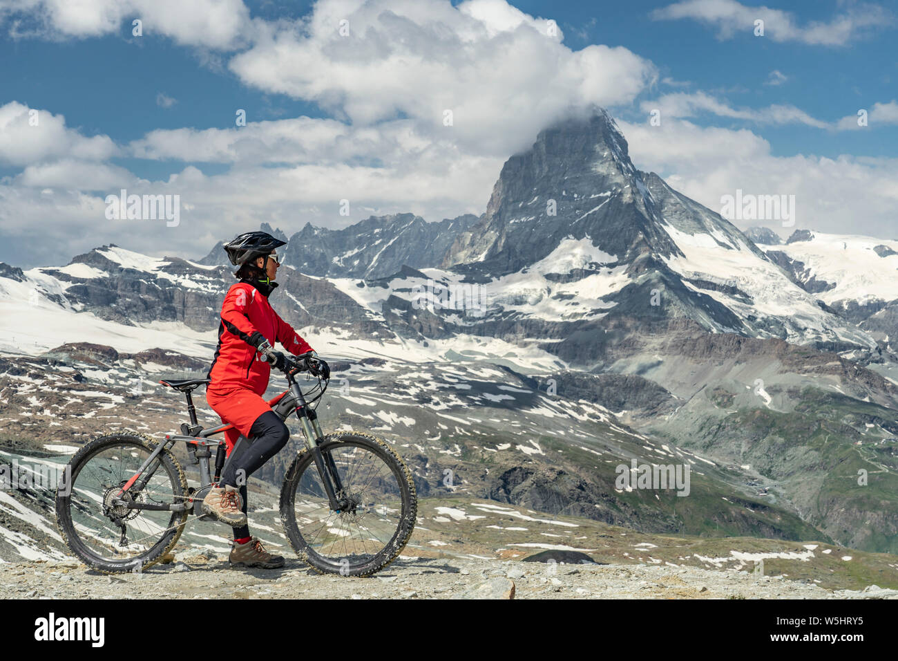 active senior woman, riding her electric mountainbike below the famous Matterhorn in Zermatt, Wallis,Switzerland Stock Photo