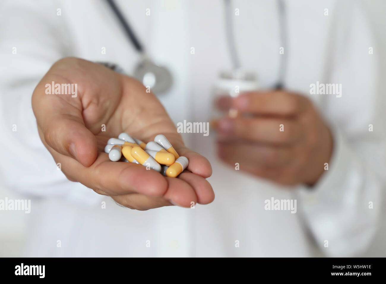 Doctor with pills, physician giving medication from bottle with capsules. Concept of dose of drugs, vitamins, medical prescription, pharmacy Stock Photo