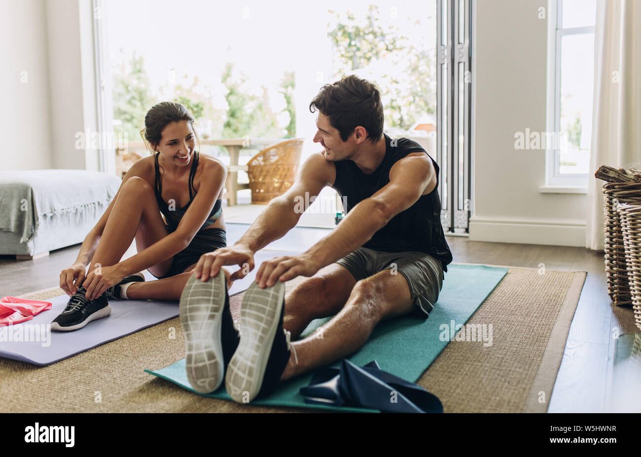 Couple exercising together. Man and woman in sports wear doing workout at home. Stock Photo