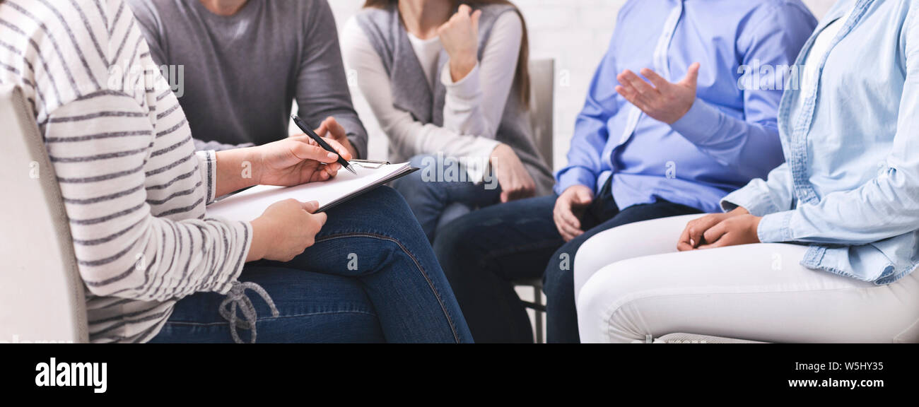 Psychiatrist listening to patients, noting down to clipboard Stock Photo