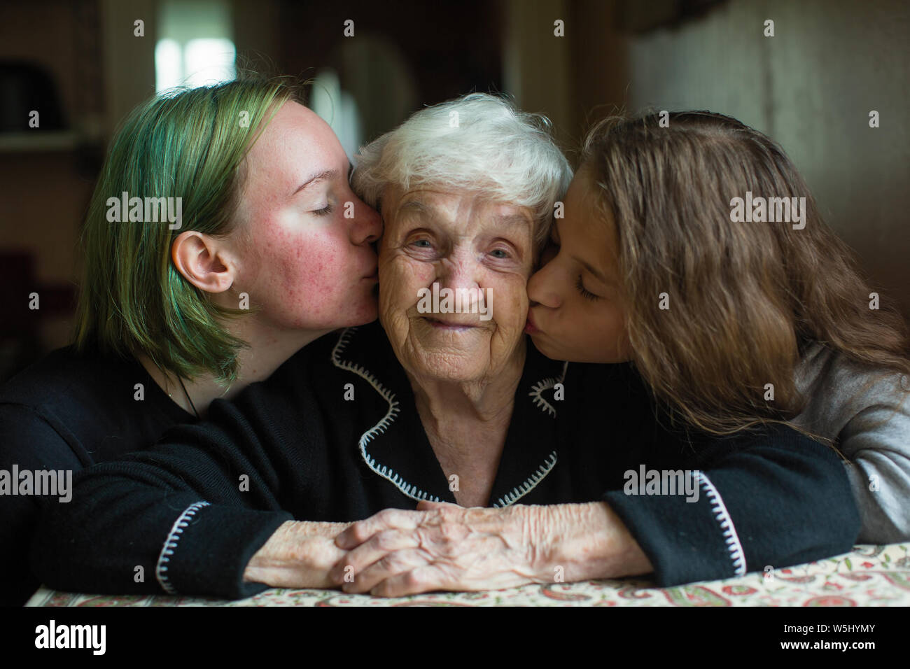 Two girls kissing their grandmother. Stock Photo