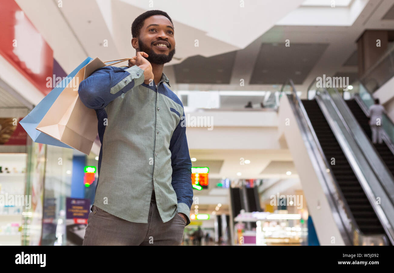 Handsome african man with purchases waiting for girlfriend Stock Photo