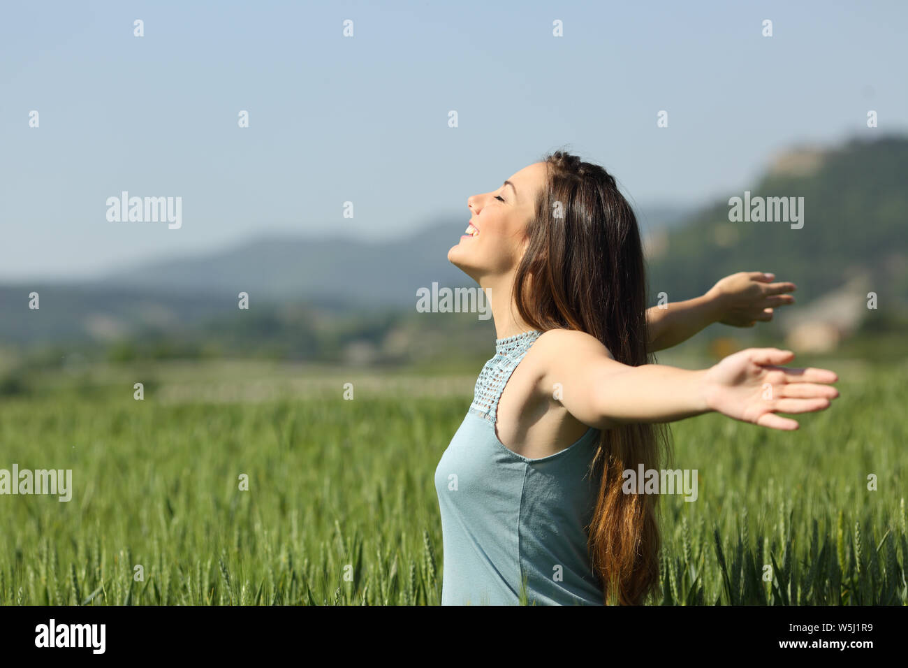 Side view portrait of a happy woman breathing deeply fresh air in a ...