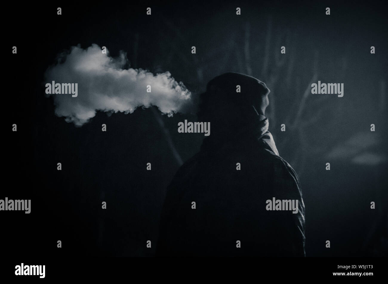 strange man smoking at night with big steam effect from the cigarette Stock Photo