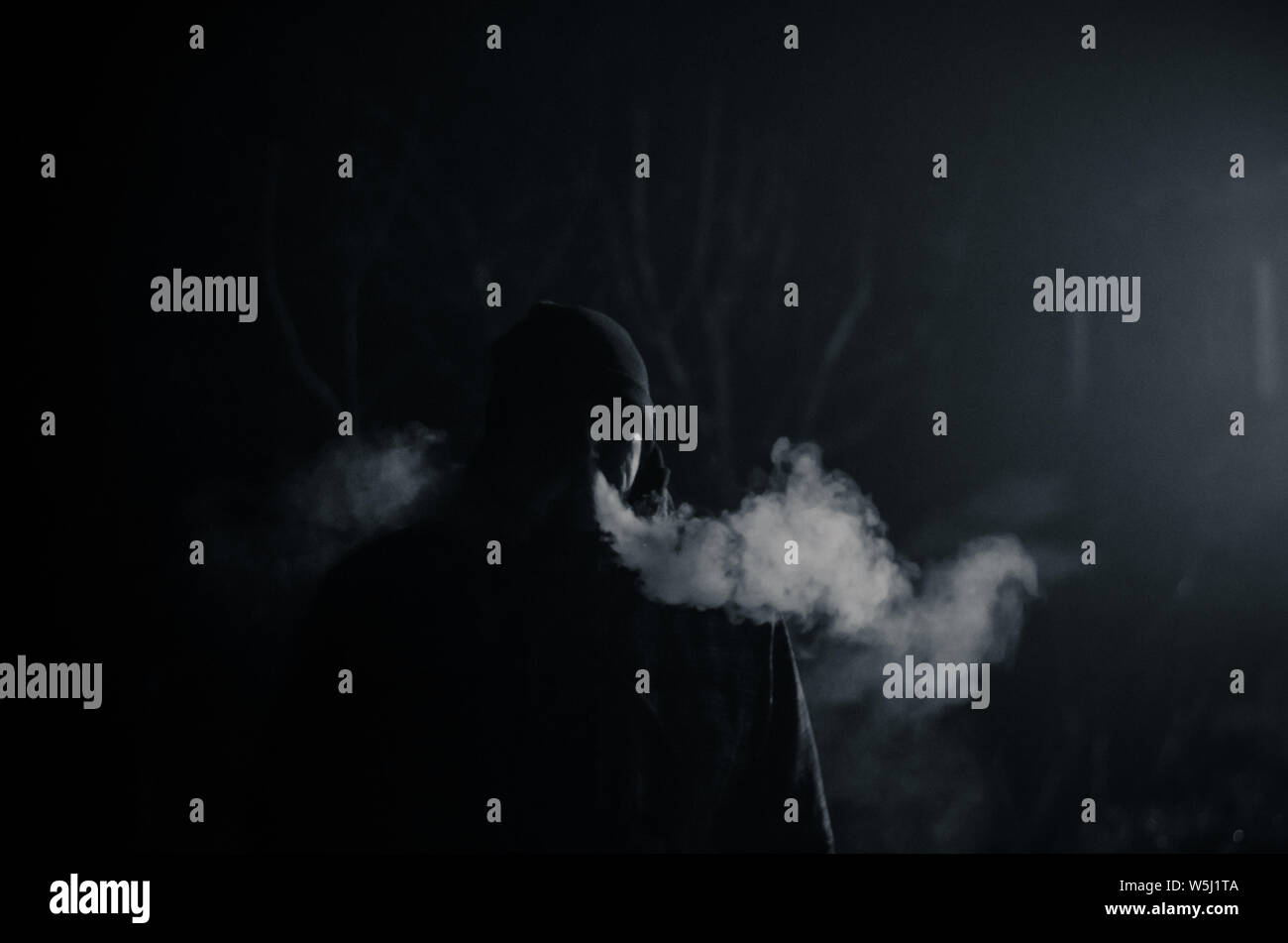 man silhouette smoking like chimney at night with backlight Stock Photo