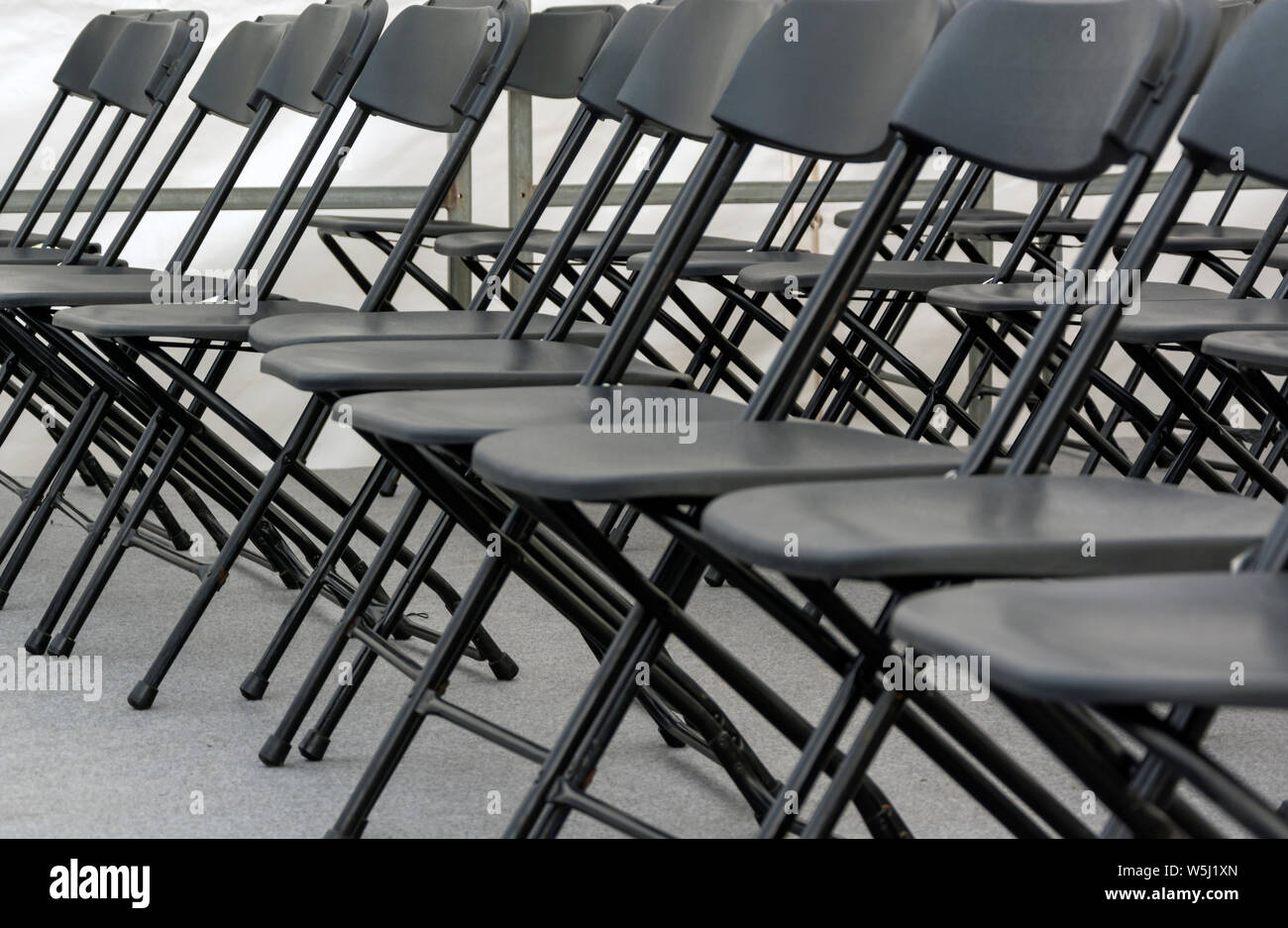 numerous folding chairs arranged in a row in a conference room Stock