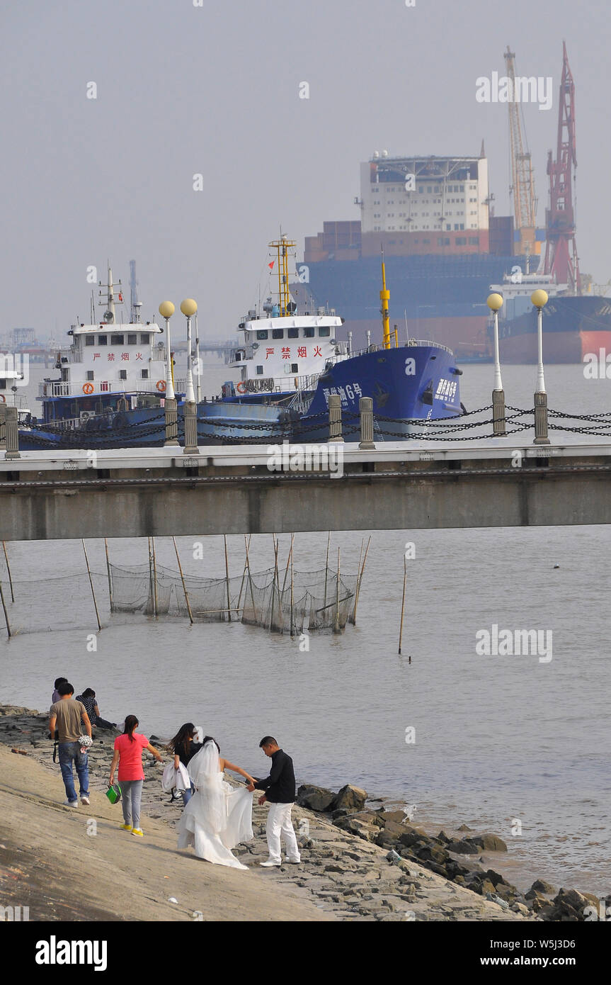 A couple of newly weds having their wedding photos taken on the banks of the Yangtse river Nantong China Stock Photo