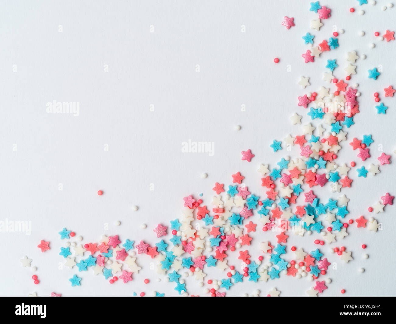 Festive border frame of colorful pastel sprinkles on white background