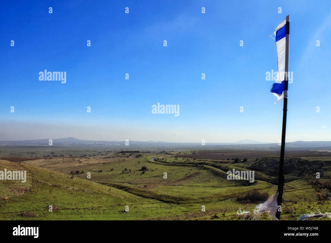A wind-blown partial Israeli flag flaps in the breeze overlooking the vast Valley of Tears in the Golan Heights. Stock Photo