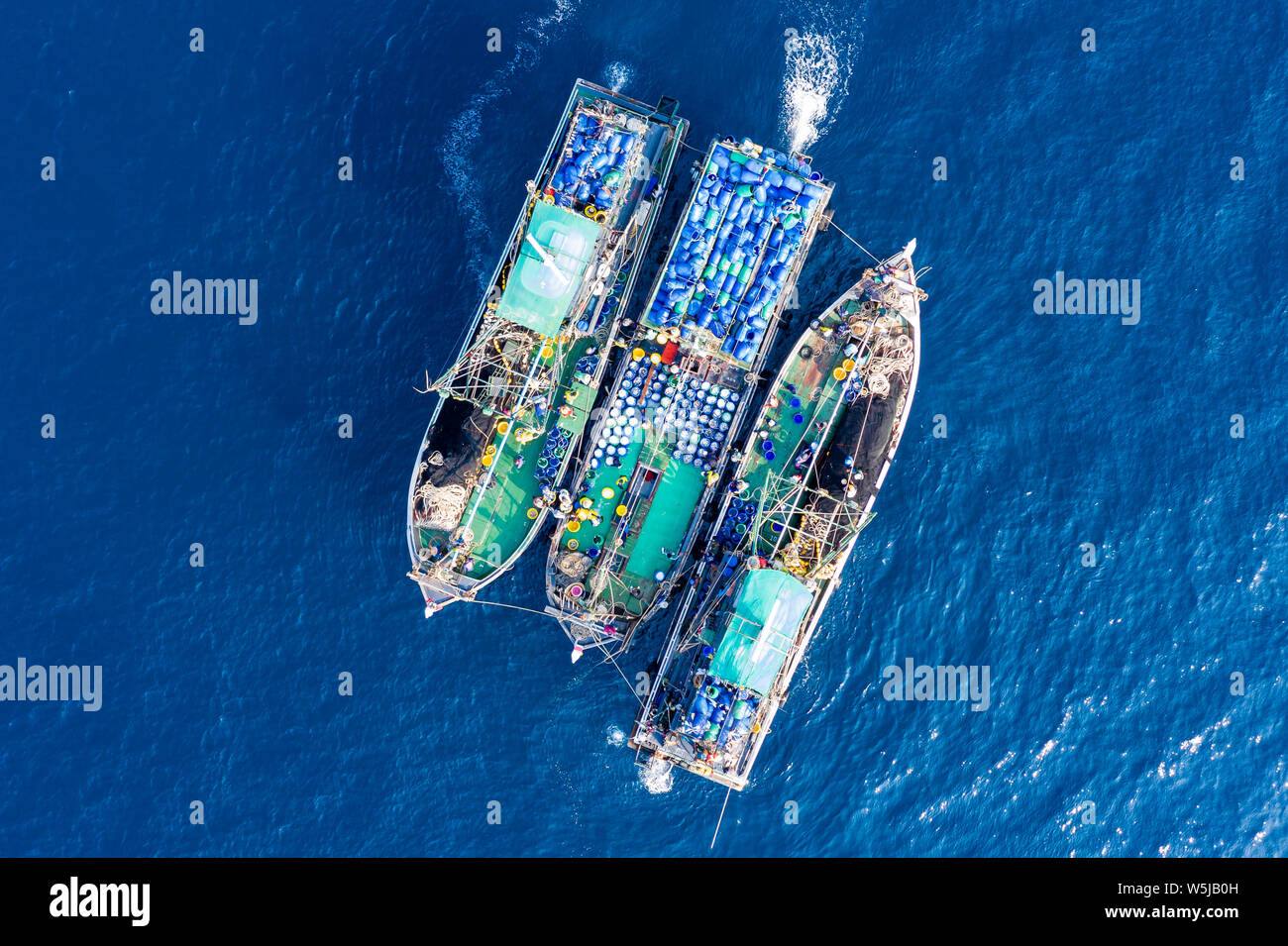 Industrial fishing - aerial view of large fishing trawlers sorting and transferring a large catch between vessels Stock Photo