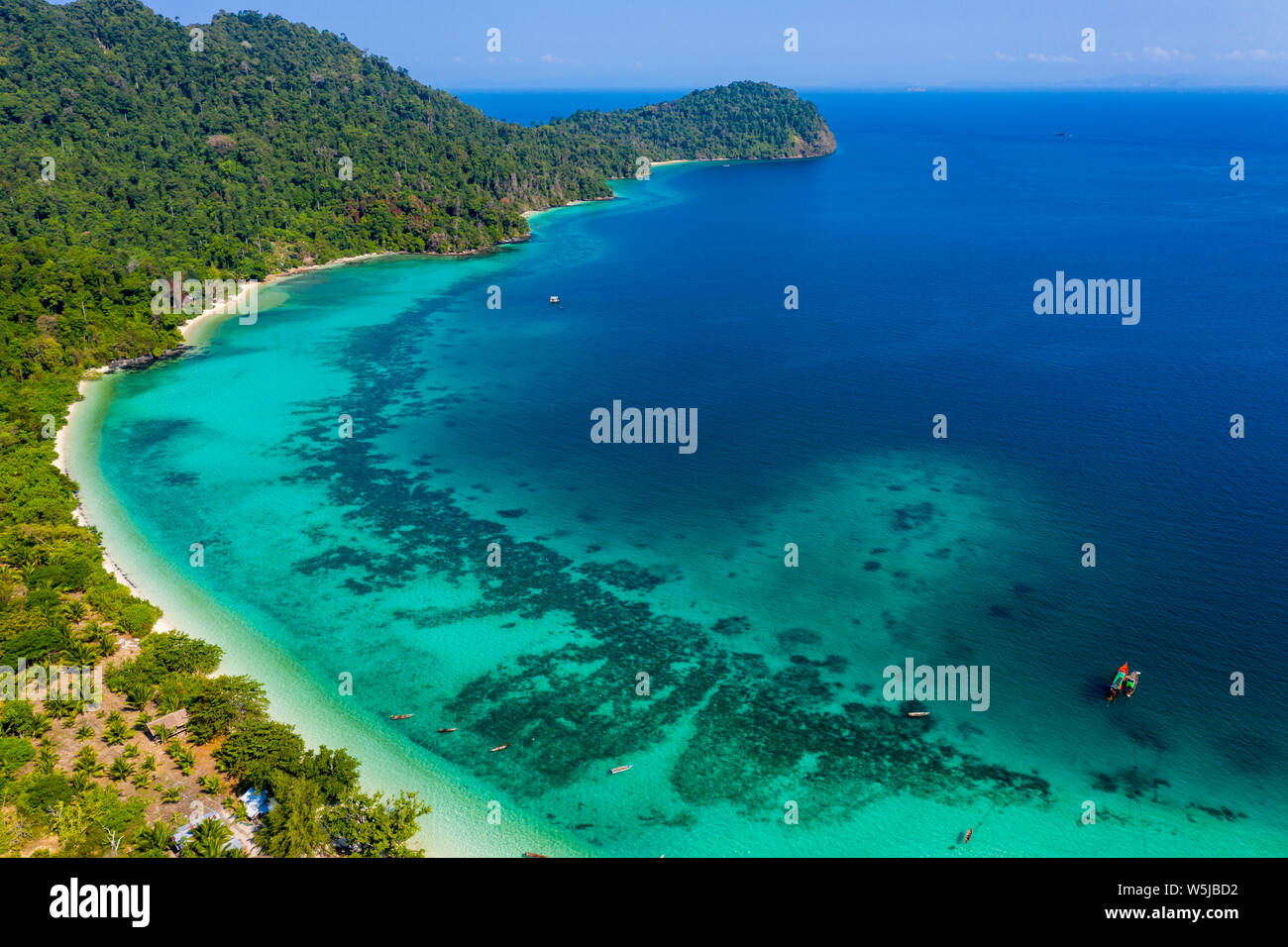 Aerial drone view of a beautiful tropical island surrounded by coral reefs and covered with lush, green jungle (Kyun Phi Lar, Myanmar) Stock Photo