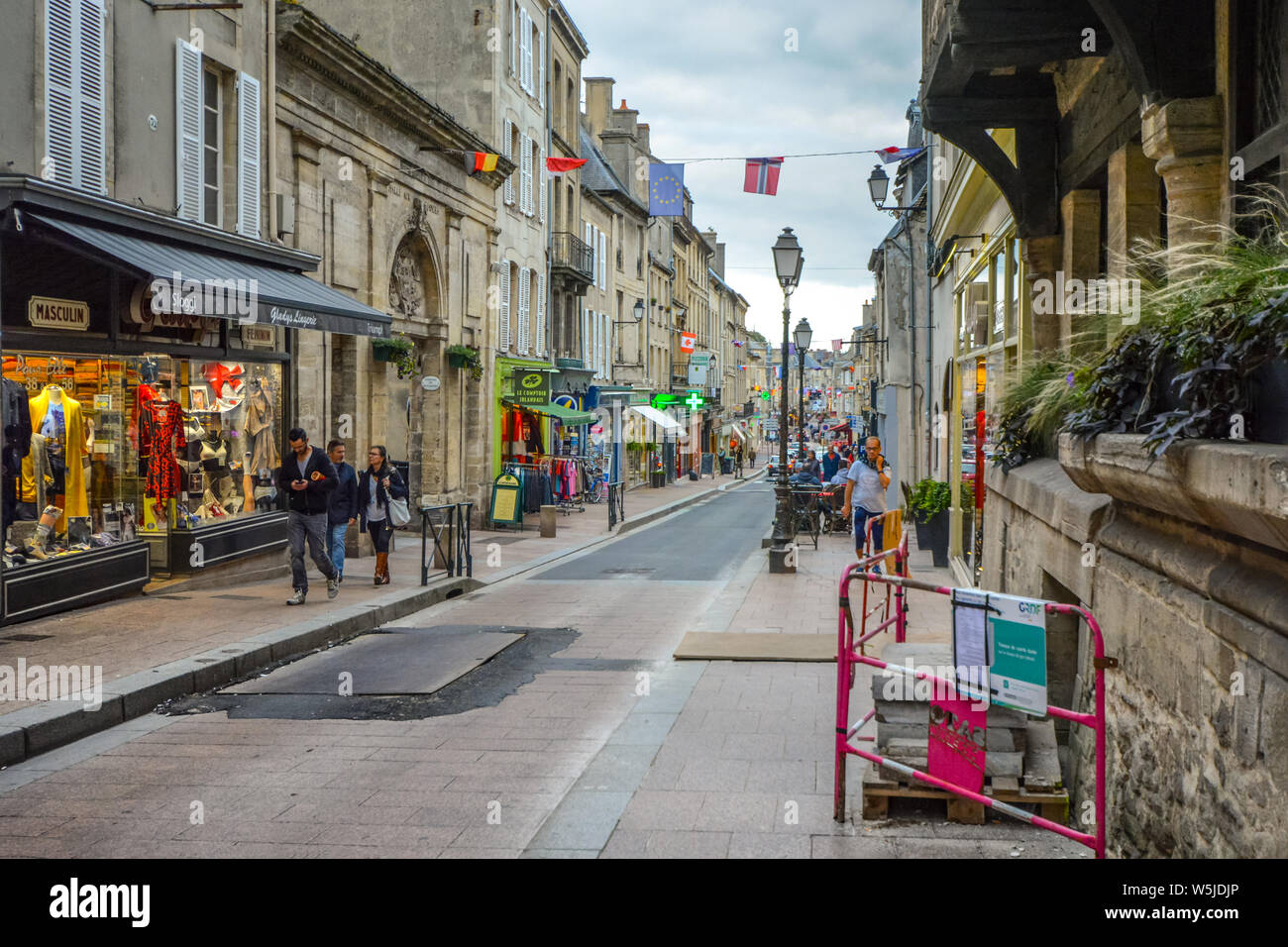 Tourists and local French walk past shops on the main street, Rue Saint