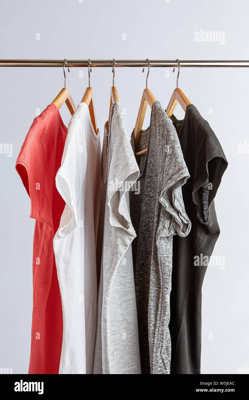 Capsule wardrobe concept. T-Shirts in neutral colors hanging on a clothing rack. Minimalist wardrobe. Stock Photo