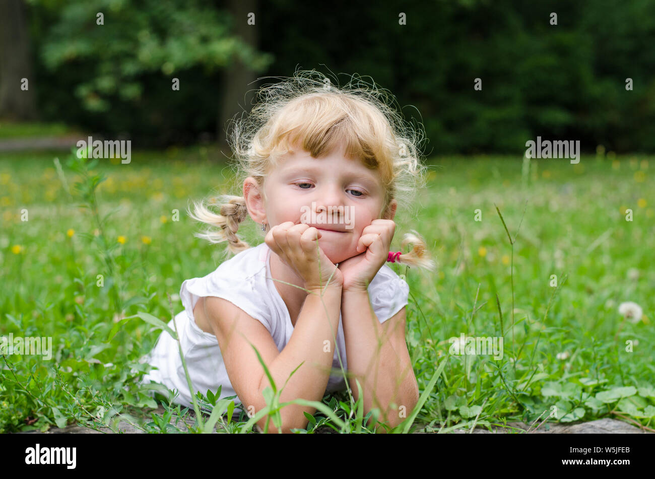 beautiful blond girl lying on meadow Stock Photo