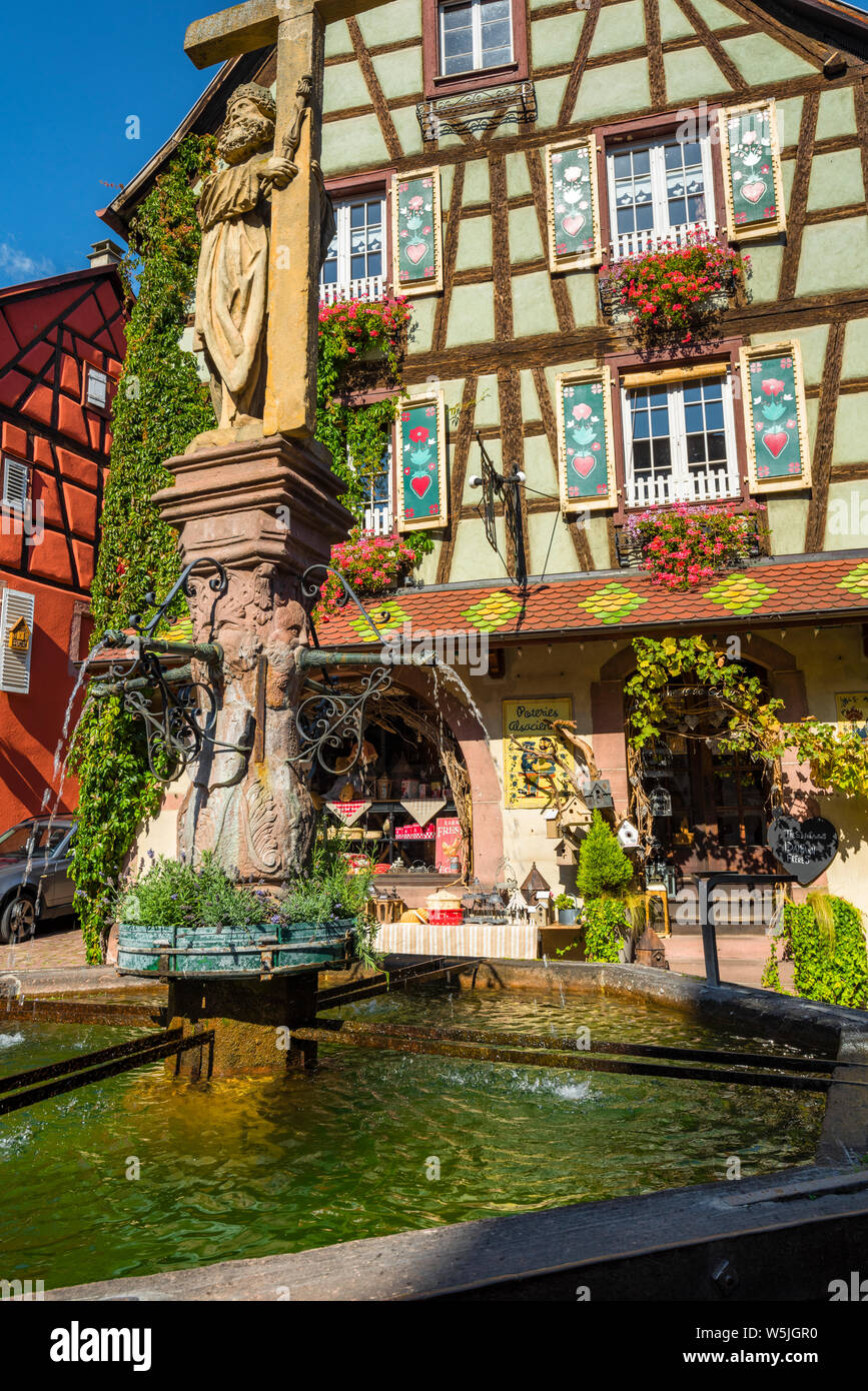 colorful half-timbered house with paintings in the town Kaysersberg, Alsace Wine Route, France, ancient well in front Stock Photo