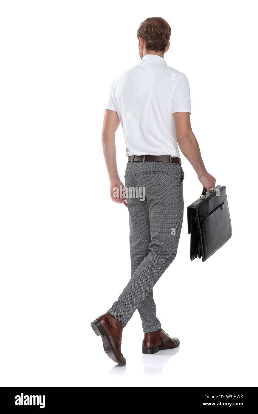 back view of a young smart casual man walking with a briefcase and ...