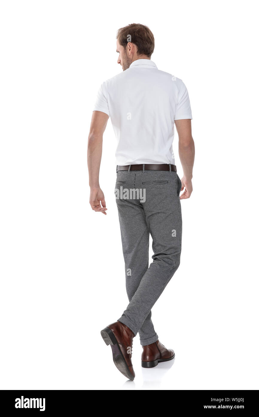back view of a walking young casual man looking to side on white ...