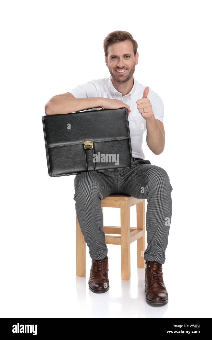 confident young smart casual man sitting and holding briefcase makes ...