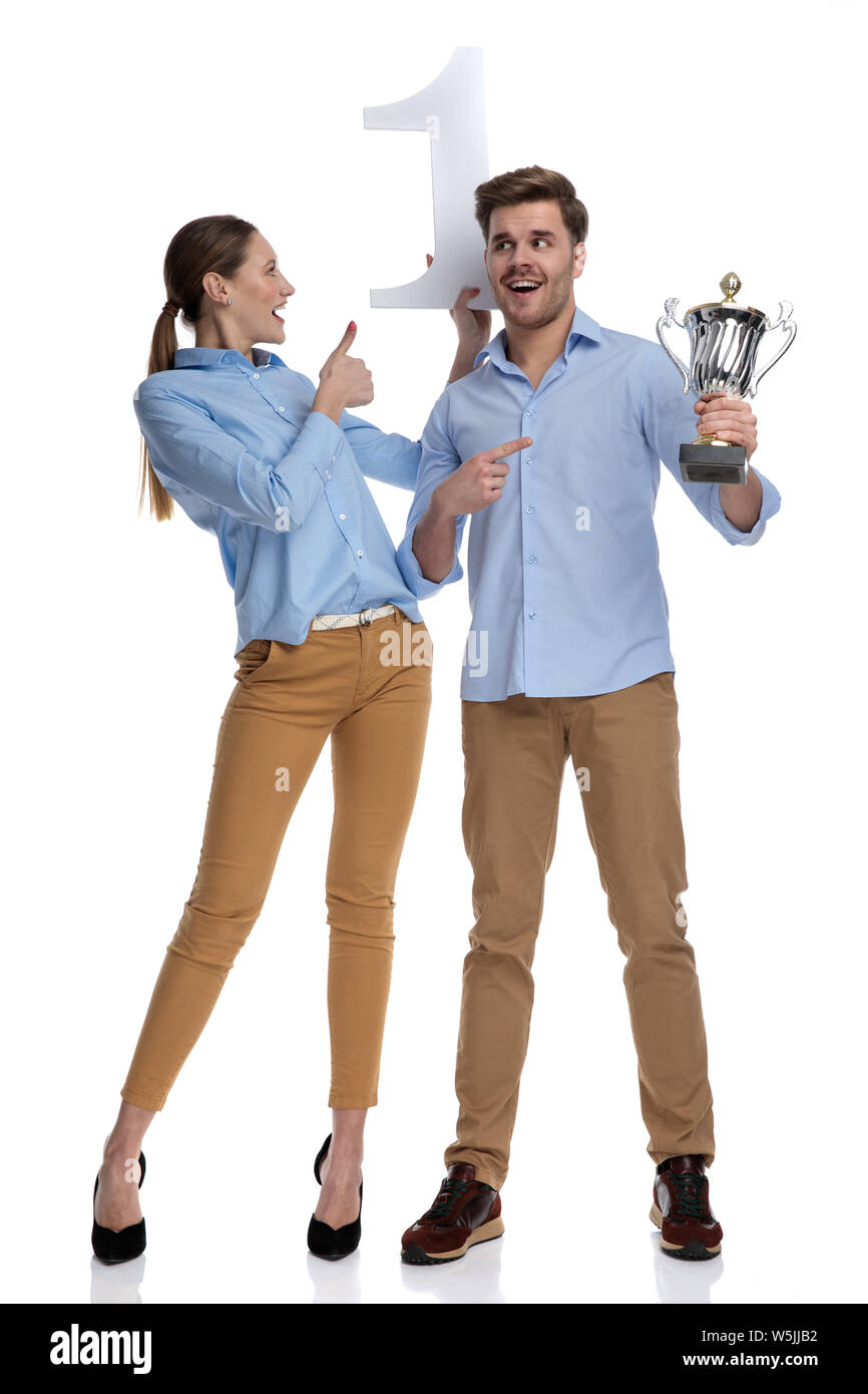 excited young casual couple holding a trophy and a number one , man ...