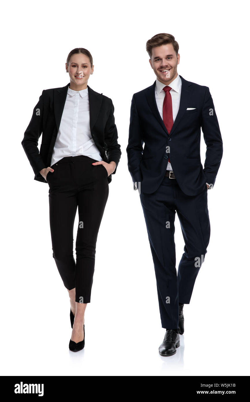 couple in business suits walking with hands in pockets on white background Stock Photo