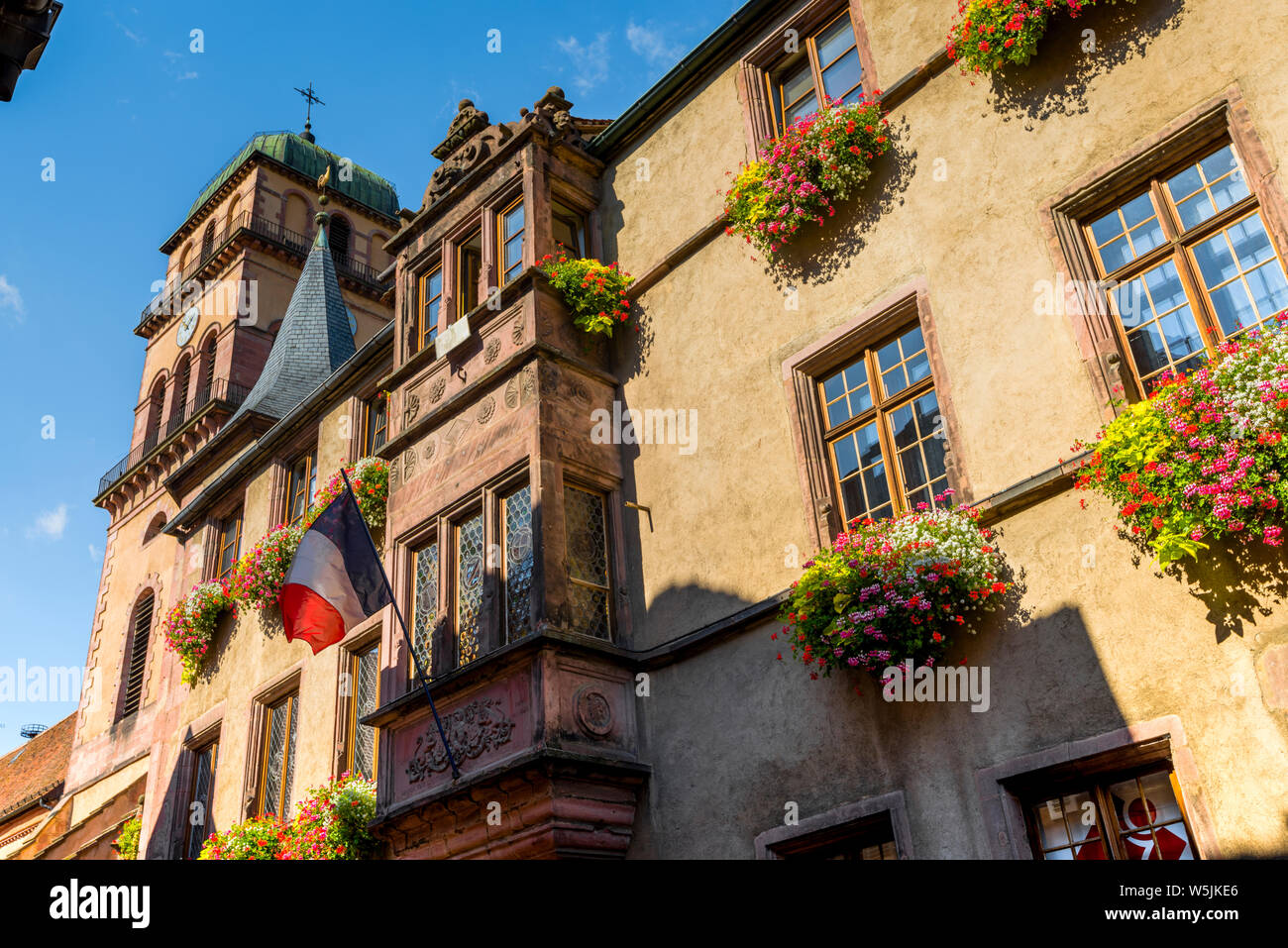 town hall of the village Kaysersberg, Alsace Wine Route, France, front with tricolor flag and flower decoration Stock Photo