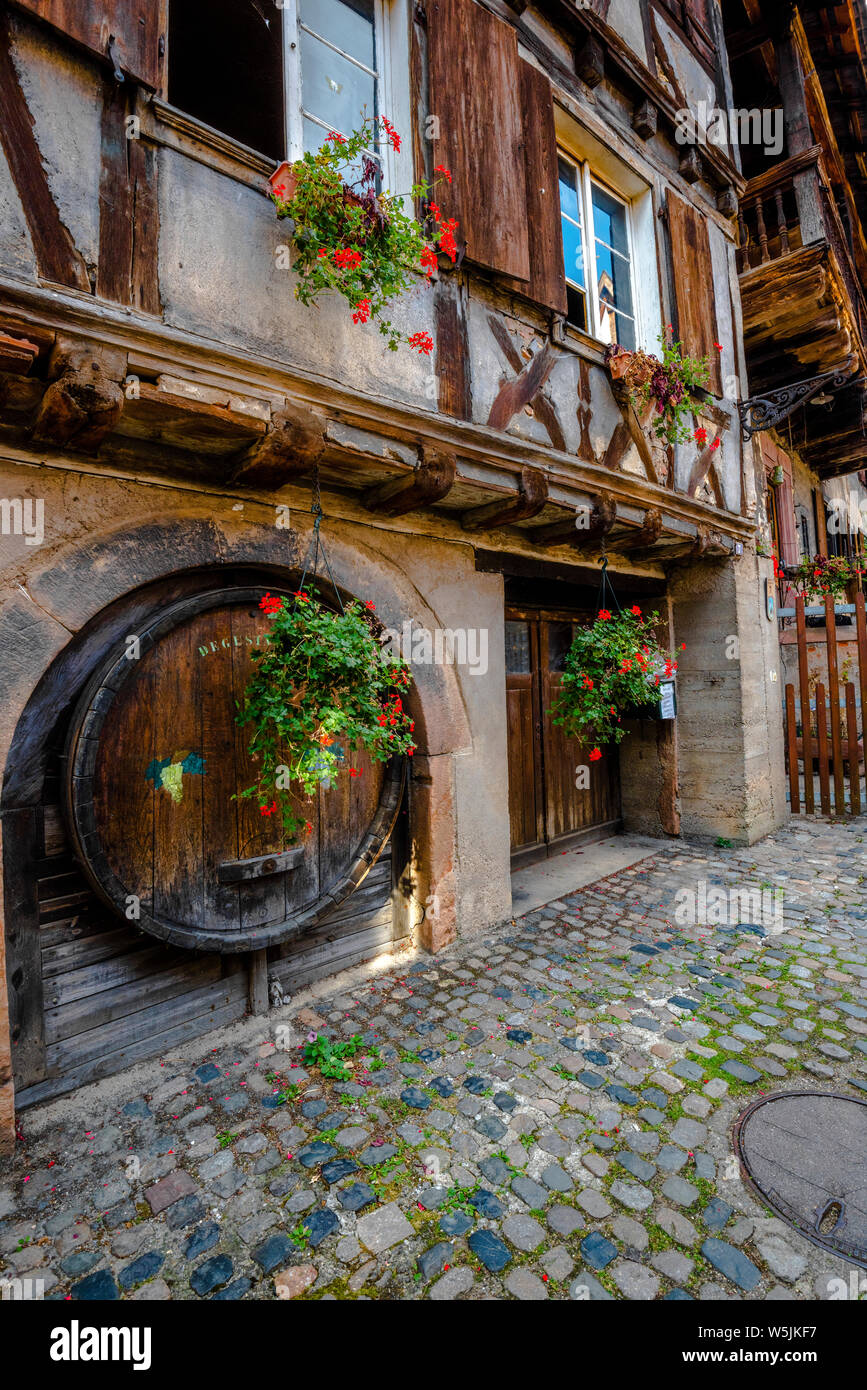 old timbered house in the village Bergheim, Alsace, Wine Route, France, wooden gate and wine barrel integrated in the house facade Stock Photo
